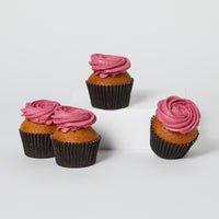 A set of three cupcakes with pink icing, presented on a white surface.