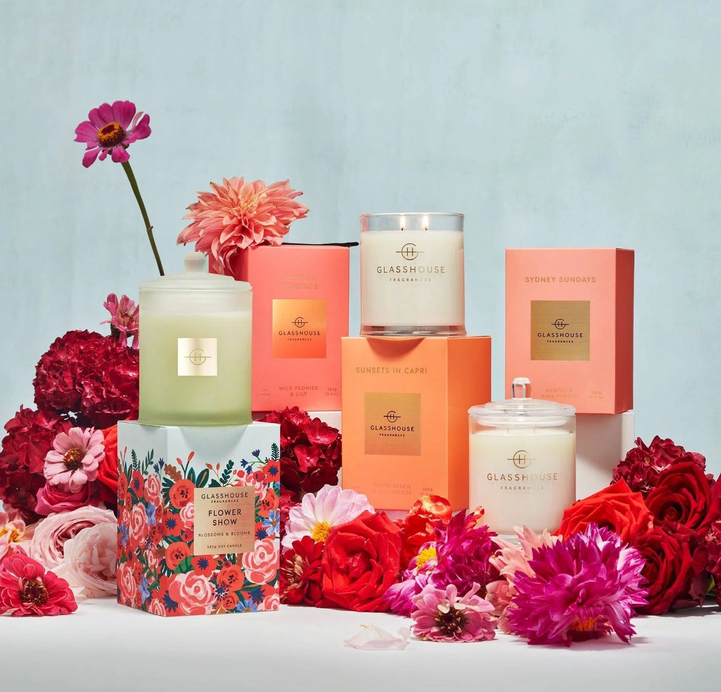 Glasshouse Fragrances candles in floral packaging surrounded by colorful flowers