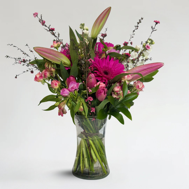Pink lily and gerbera bouquet with mixed seasonal flowers in clear glass vase